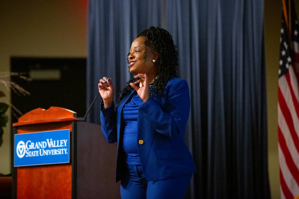 TaRita Johnson, in blue outfit, speaks next to a podium on stage